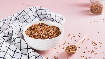 Raw buckwheat in a bowl and wooden spoon on the table web banner photo
