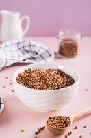 Raw buckwheat in a bowl and wooden spoon on the table vertical view photo