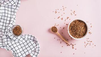 White bowl with raw whole grain buckwheat on pink background top view web banner photo
