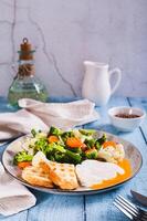 Mix of boiled vegetables, poached egg and waffle toast on a plate on the table vertical view photo