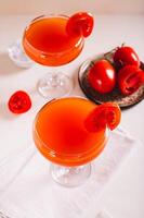 Original tomato martini cocktail in glasses and tomatoes on a plate on the table vertical view photo