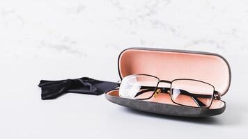 Eyeglasses in open hard case and cleaning cloth on table web banner photo