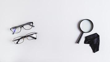 Pair of eyeglasses, magnifier and cleaning cloth on blue background top view web banner photo