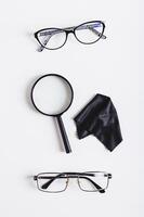 Choice concept, pair of eyeglasses, magnifying glass and cleaning cloth top and vertical view photo