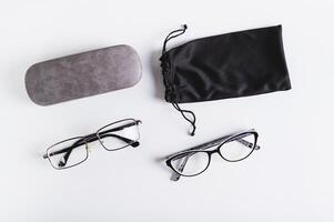 Eyeglasses, hard and soft storage case on blue background top view photo