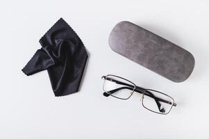 Metal frame eyeglasses, hard case and cleaning cloth on blue background top view photo