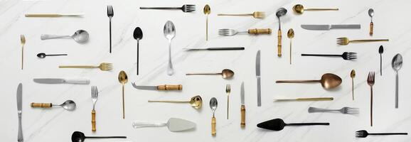 knives, forks, spoons and cutlery seen from above on white marble background photo