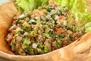 Tabbouleh, classic Arabic dish with vegetables and wheat photo