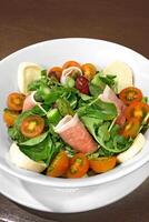 salad in bowl with green leaves, buffalo mozzarella and cherry tomatoes photo