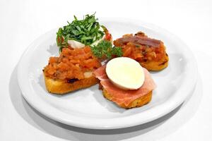 bruschetta with aliche, parma ham, mozzarella and chopped tomatoes photo