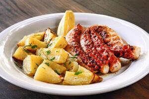 grilled octopus with rustic potatoes on plate photo