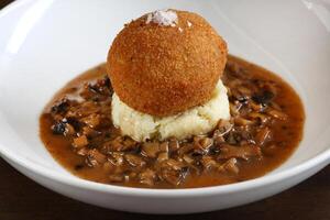 Egg Mollet breaded with mashed potatoes and dry mushroom sauce photo