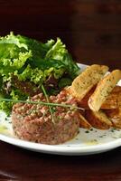 Steak Tartare with leaf salad and rustic potatoes photo