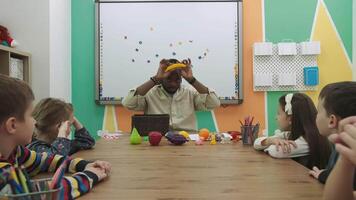 un africano americano profesor enseña un grupo de niños 10-12 años viejo, estudiando animales y frutas.escuela para niños, enseñando adolescentes, ganancia conocimiento, aprender el idioma. video