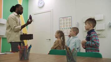 un africano americano profesor y un grupo de niños son estudiando frutas y animales en el aula.escuela para niños, enseñando adolescentes, ganancia conocimiento, aprender el idioma. video