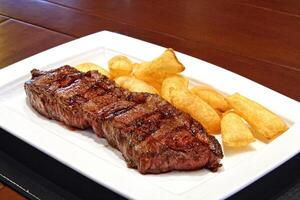 Strip Steak, classic cut of meat with stewed potatoes on the plate photo