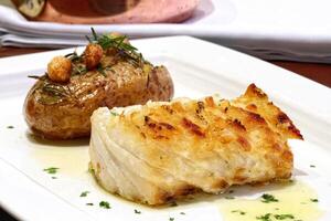 oven-baked cod with stuffed potatoes and fried garlic photo