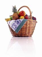 basket with grapes, orange, pineapple, mango, bananas and other fruits on white background photo