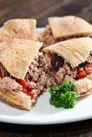 tuna sandwich on pita bread with chopped tomatoes and black olives photo