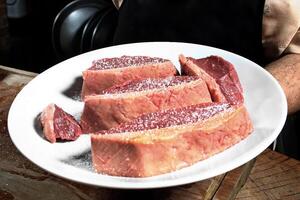 professional butcher teaching step by step how to prepare picanha, a Brazilian cut of meat photo