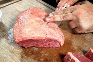 professional butcher teaching step by step how to prepare picanha, a Brazilian cut of meat photo