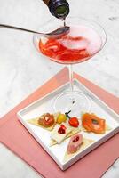 champagne cocktail with small canapes on plate photo