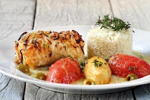 al horno bacalao filete con cebollas, papas, Tomates y arroz foto