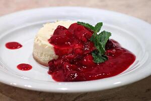 cheesecake with red fruit syrup on plate photo
