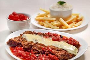 filet parmigiana with fries, rice and cherry tomatoes photo