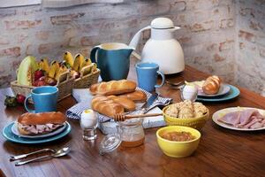 desayuno con jamón, queso, huevos y un pan en el mesa foto