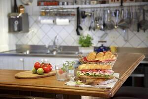 large sandwich of ham, cheese and tomatoes on the kitchen table photo