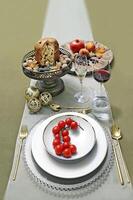 plato con Tomates en mesa con Panettone, anteojos, Fruta y vino foto