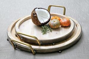 coconut and pumpkins on wooden platter on the table photo