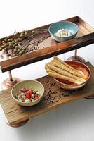 bronze and wooden tray with snacks, pepper and flowers photo
