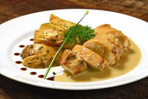 stuffed chicken and rustic potatoes on plate photo