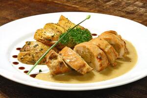 stuffed chicken and rustic potatoes on plate photo