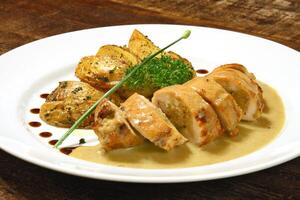 stuffed chicken and rustic potatoes on plate photo