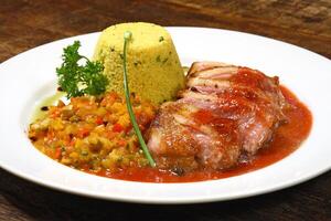 roast duck with sauce and Moroccan couscous on plate photo