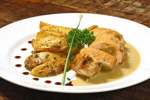 stuffed chicken and rustic potatoes on plate photo