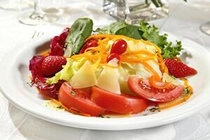 Tropical salad with lettuce, tomatoes, cheese, carrots and strawberries photo