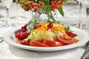 Tropical salad with lettuce, tomatoes, cheese, carrots and strawberries photo