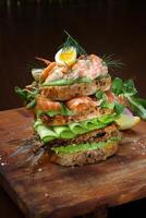 Smorgastarta, Swedish sandwich with fish, mayonnaise, eggs, sliced cucumber, smoked tuna and prawns on rye bread photo