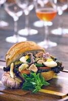 Pan Bagnat, French sandwich with tuna, aliche, tomato, garlic, lettuce, egg and mustard on bread photo