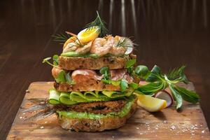 Smorgastarta, Swedish sandwich with fish, mayonnaise, eggs, sliced cucumber, smoked tuna and prawns on rye bread photo