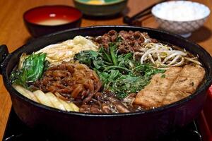 Sukiyaki, Japanese dish with sliced filet, butter, soy sauce, sugar, shitake, chard and tofu photo