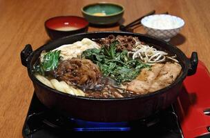 Sukiyaki, japonés plato con rebanado filete, manteca, soja salsa, azúcar, mierda, acelga y tofu foto