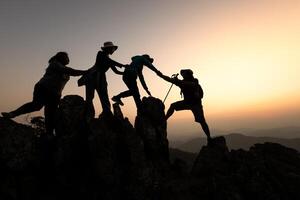 silueta de caminantes alpinismo arriba en el montaña, equipo trabajo y Ayudar concepto. trepador éxito. foto