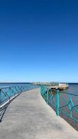 vertical foto de muelle para caminar por el mar en contra el fondo de claro azul cielo en caliente verano día