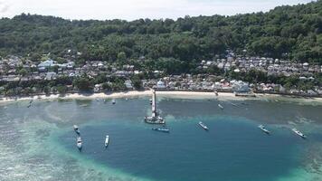 antenne visie van motor boten aangemeerd Aan rennen eiland met stelten huizen Bij de terug Aan houten dek. helder blauw lucht.. maluku, Indonesië, april 18, 2024 video