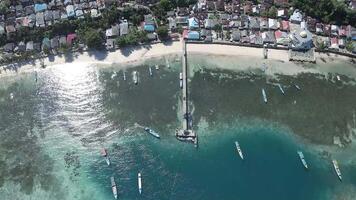 antenne visie van motor boten aangemeerd Aan rennen eiland met stelten huizen Bij de terug Aan houten dek. helder blauw lucht.. maluku, Indonesië, april 18, 2024 video